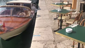 Petit bateau inboard en bois accosté sur les quais de Sète au bord d'une terrasse de restaurant. 